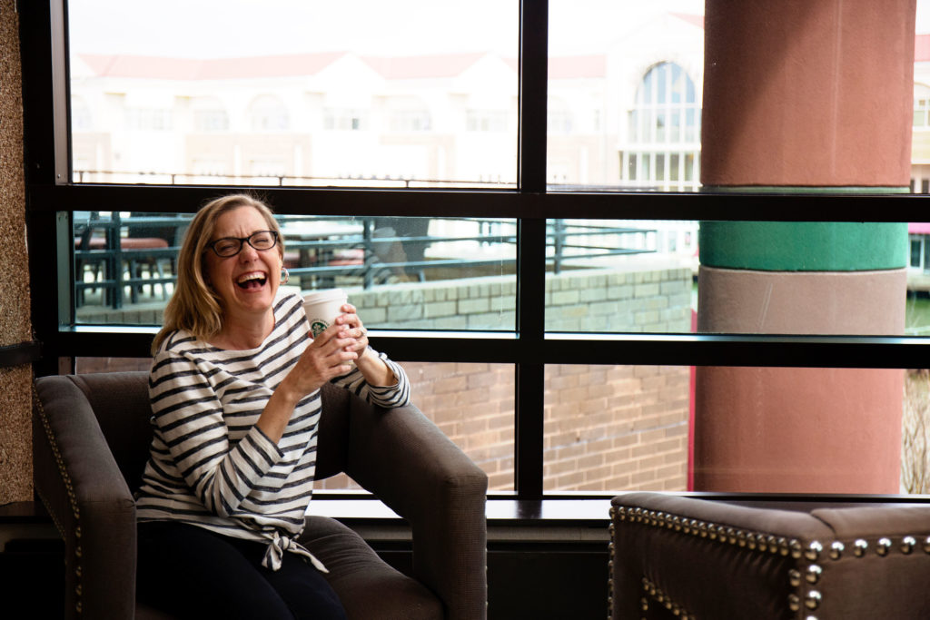 Karen, the creator of Convos with Karen, laughing while holding a cup of coffee