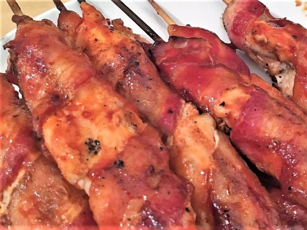 Bacon wrapped chicken tenders, brushed with barbecue sauce and skewered