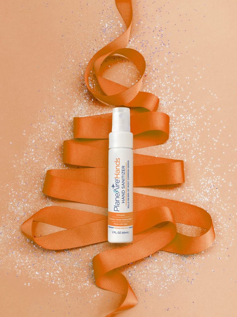 PlaneAire Hands in orange pineapple laying on an orange ribbon christmas tree with glitter
