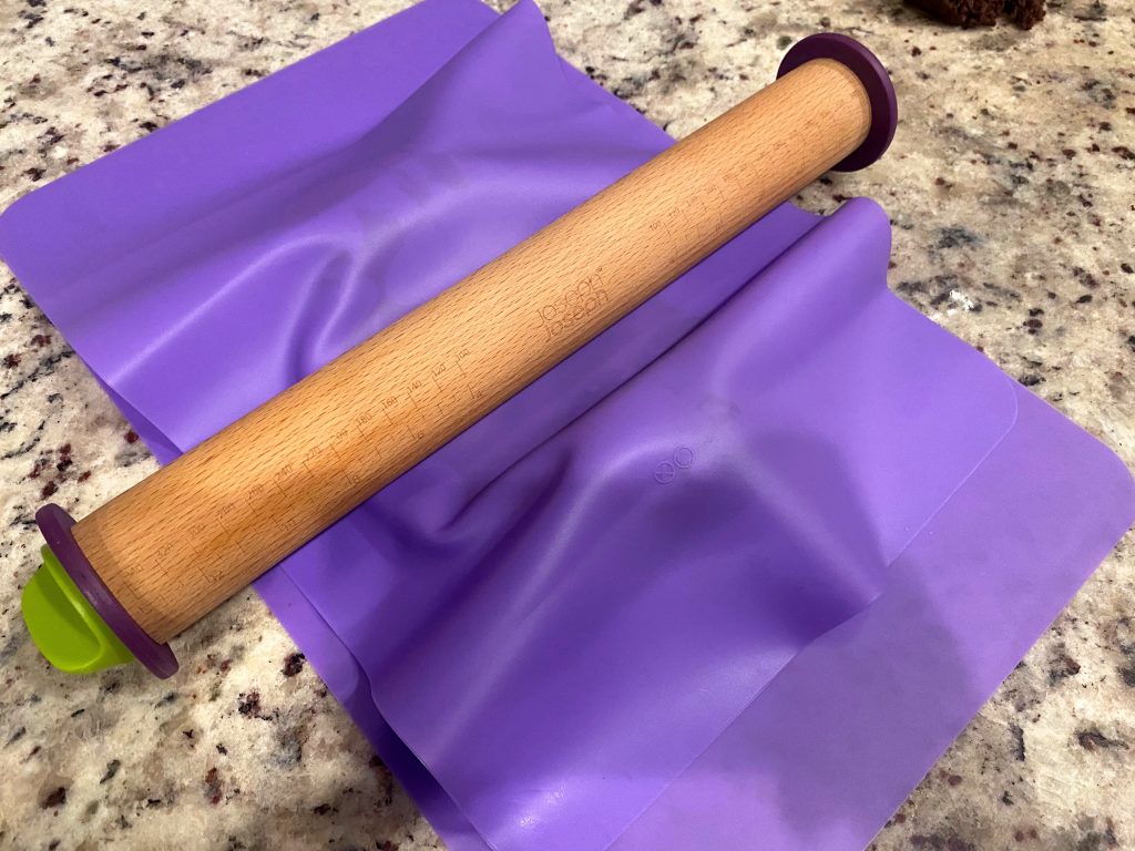 Purple silicone mats with rolling pin, used to keep dough from getting sticky or crumbly for perfect sugar cookies every time