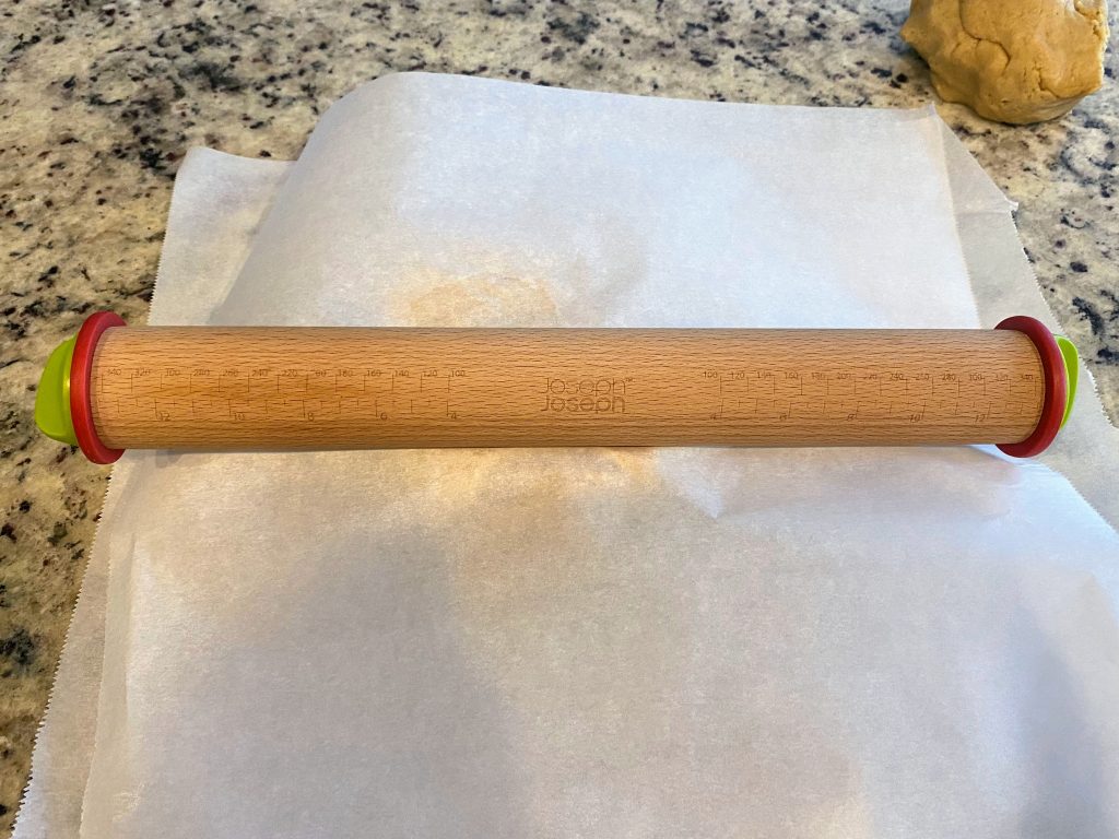 Rolling pin with thickness rings on parchment paper. Essential tool for perfect sugar cookies.