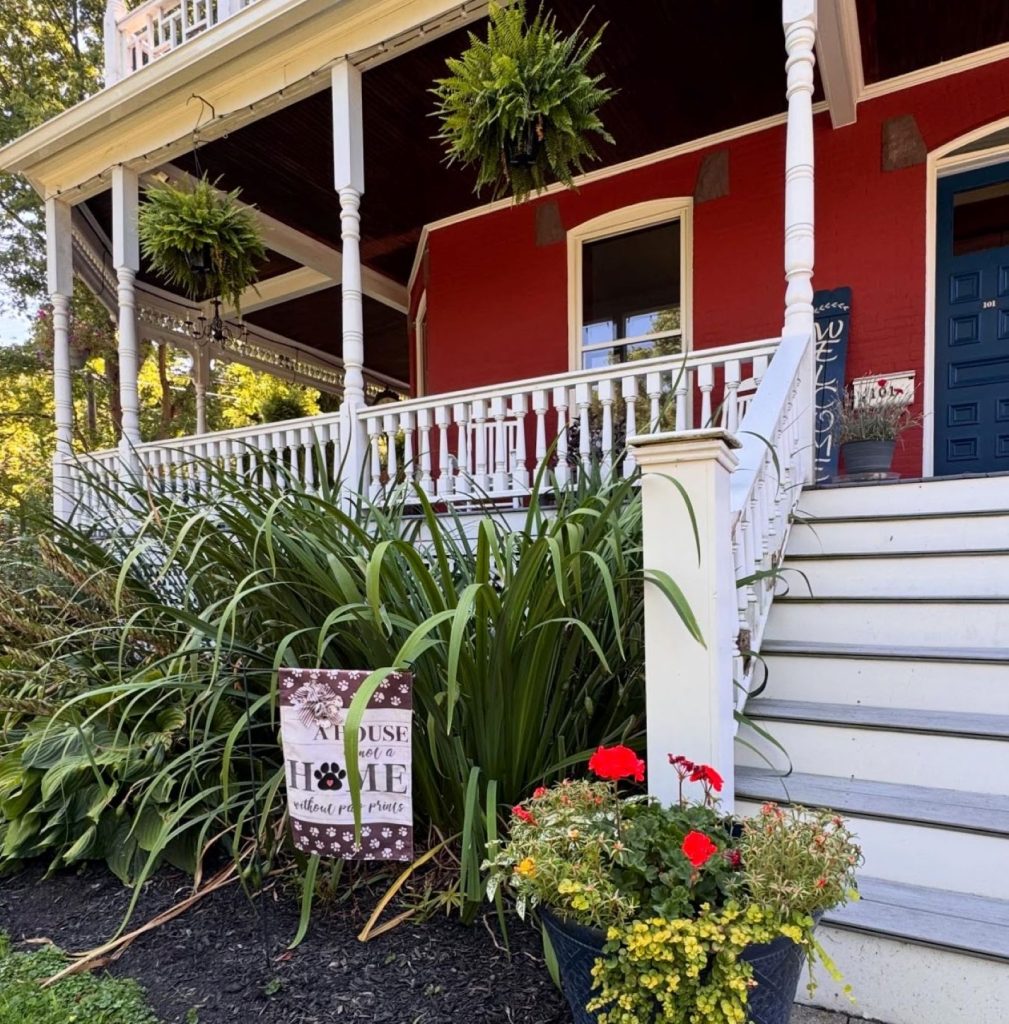White stairs and rail with flower baskets and welcome signs.