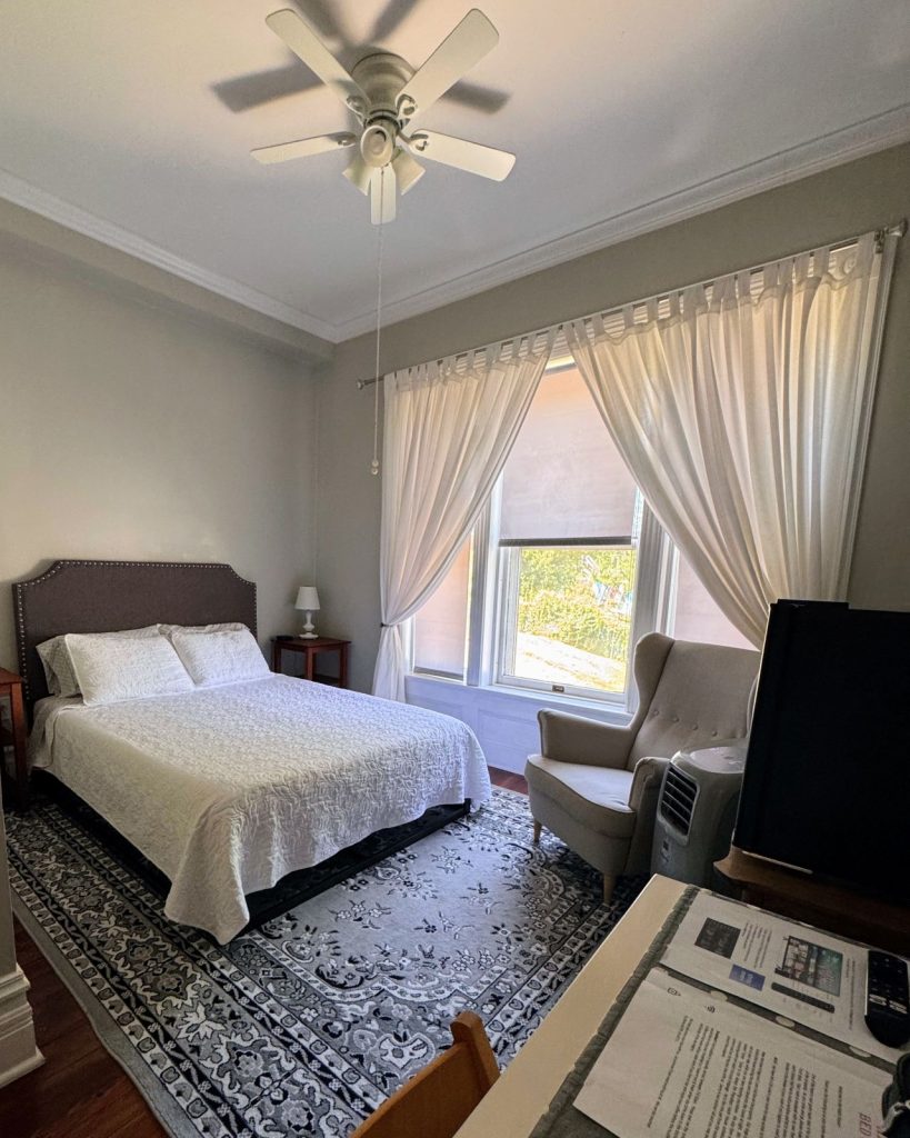 The Bradford Room at Hatch House, showing bed, large window, seating area and rug.